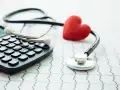 Kalkulator, stetoskop i czerwone serce na tle EKG. Obrazek sugeruje, ile wynosi dobrowolne ubezpieczenie chorobowe.