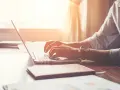 Mężczyzna w białej koszuli pisze na laptopie, zastanawiając się, po jakim czasie dzwonią w sprawie pracy.