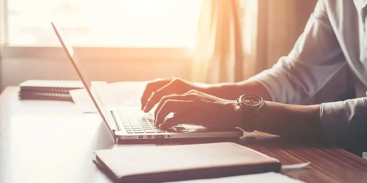 Mężczyzna w białej koszuli pisze na laptopie, zastanawiając się, po jakim czasie dzwonią w sprawie pracy.