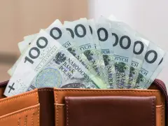 Portfel z banknotami 100 zł. Czy urlop wychowawczy jest płatny? To pytanie nurtuje wielu rodziców, a pieniądze w portfelu mogą pomóc w podjęciu decyzji.