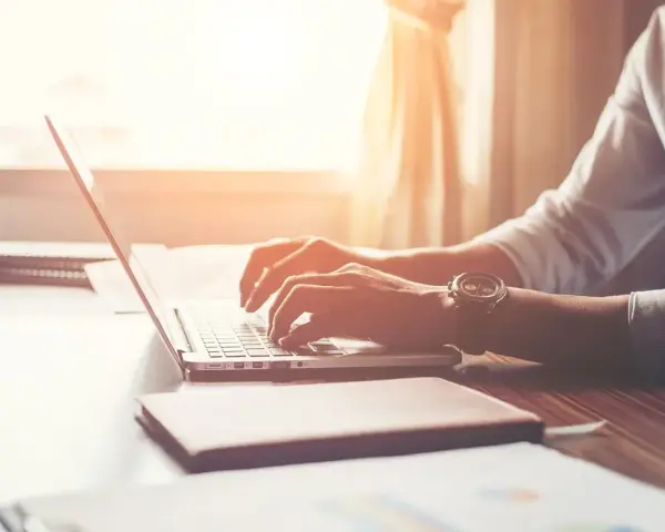 Mężczyzna w białej koszuli pisze na laptopie, zastanawiając się, po jakim czasie dzwonią w sprawie pracy.