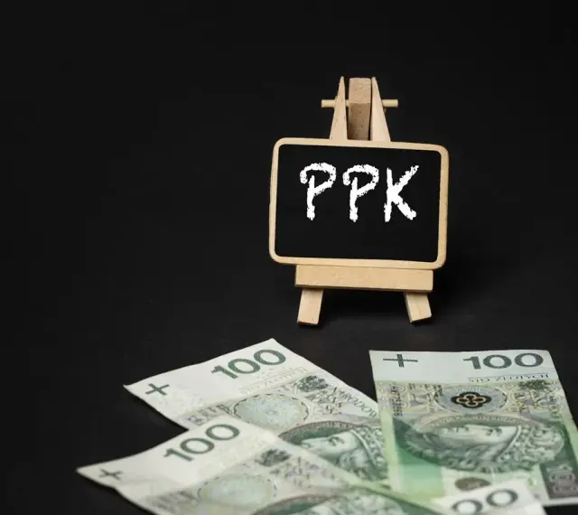 Tabliczka z napisem PPK i polskie stuzłotówki. Zastanawiasz się, ppk co to? To program oszczędzania na przyszłość.