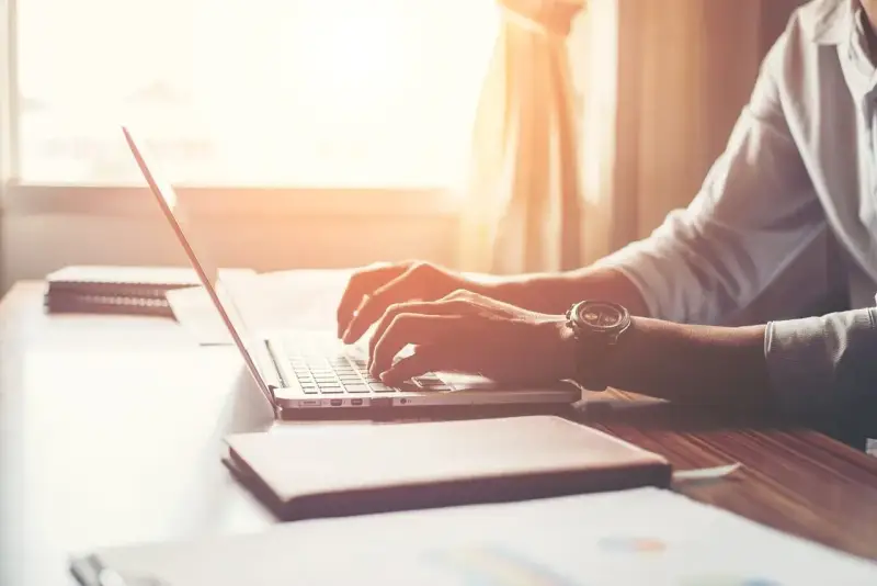 Mężczyzna w białej koszuli pisze na laptopie, zastanawiając się, po jakim czasie dzwonią w sprawie pracy.